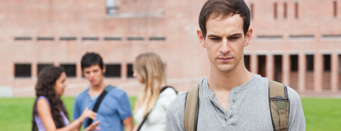 Lonely student posing while his classmates are talking