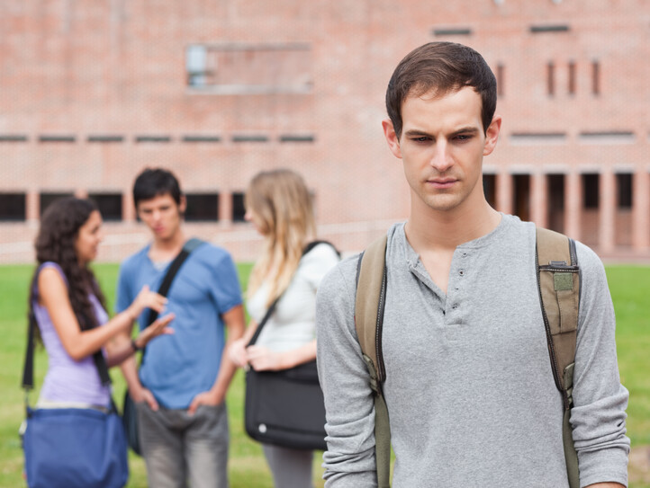 Lonely student posing while his classmates are talking